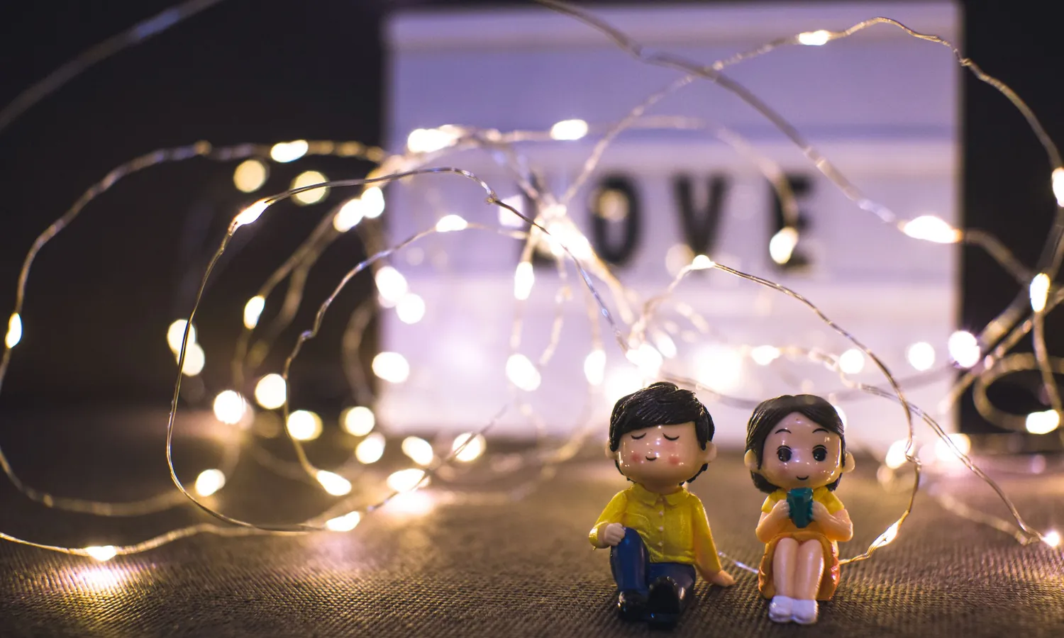 Two small figurines under warm fairy lights